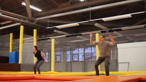 Man and woman are doing jump with turnover synchronously on a bouncer — Stock Video