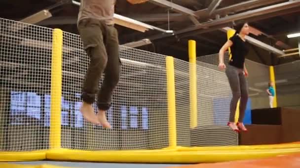 Bir erkek ve bir kadın zaman uyumlu trampolines üzerinde atlama içinde nişanlandık — Stok video