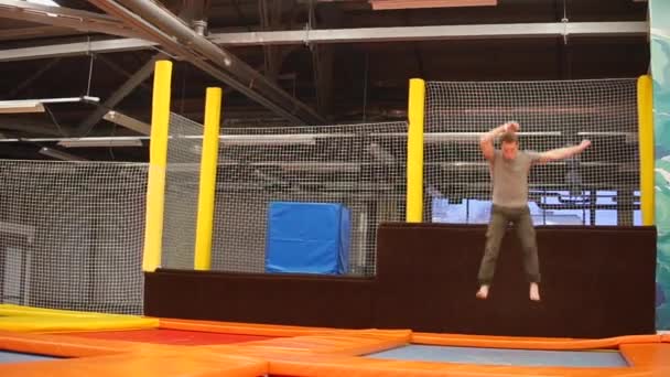 Sportsman is performing acrobatic elements on a trampoline — Stock Video