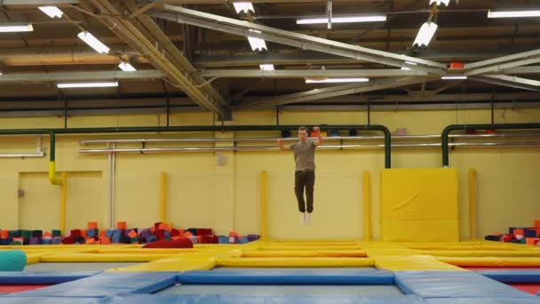 Um jovem corre ao longo do complexo de trampolim e salta para cima — Vídeo de Stock