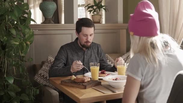 Amis mangent le petit déjeuner dans un restaurant, ils mangent du sirop sucré et croissant — Video