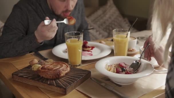 Casal casal está tomando café da manhã em um café, comer mingau e panquecas — Vídeo de Stock