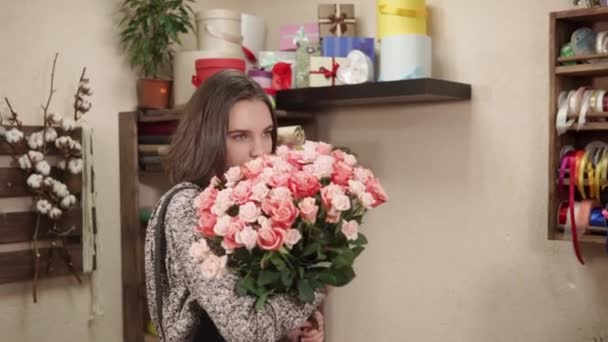 Гарна жінка нюхає букет квітів, який вона зробила в майстерні — стокове відео