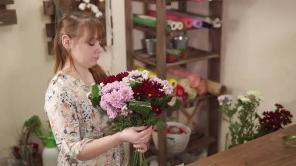 Флорист собирает цветочные композиции, женщина держит хризантемы в руках — стоковое видео