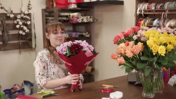 Young woman demonstrates a bouquet which she collected in a flower shop — Stock Video