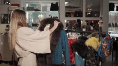 Genç kadın bir giyim mağazası bir sıcak kış ceket üzerinde çalışıyor