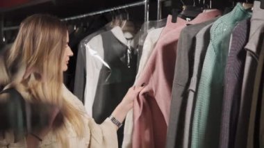 Güzel kız oluyor ürünler rafları dokunmadan giysi alışveriş merkezinde alışveriş