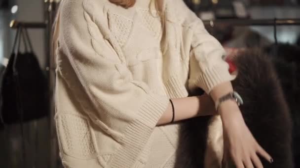 Slanke vrouw probeert op een denim vest met bont in een winkel — Stockvideo