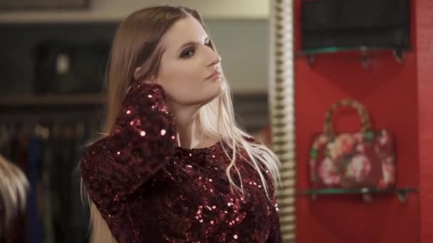 En ung och vacker kvinna med blont hår undersöker sin nya bild i spegeln — Stockvideo