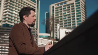 Düşünceli adam şehirde taş çit üzerinde güneşli bir günde, hava nefes meyilli