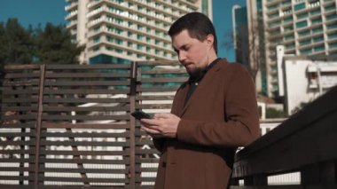 genç adam Şehir alanının içinde sokakta duruyor ve sms Smartphone'da yazdırır