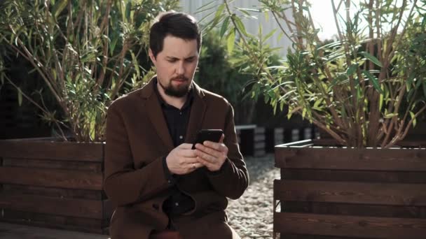 Man resting in a park with cell phone — Stock Video