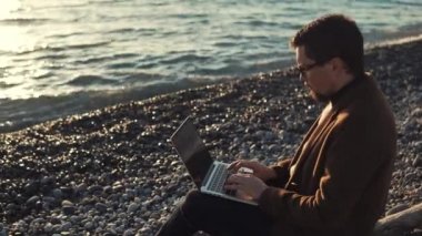 İşadamı dizüstü bilgisayar ve internet kullanma deniz kıyısında akşam çalışıyor