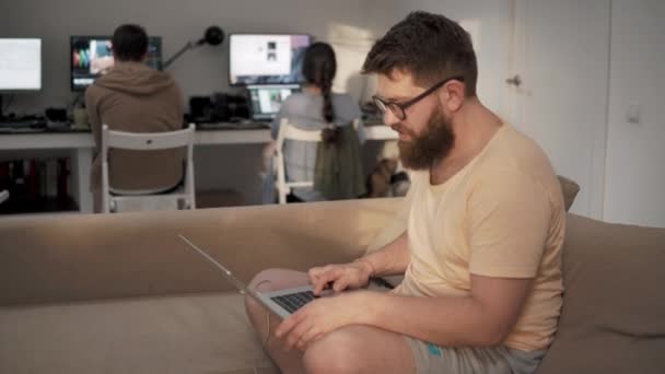 Jovem em casa roupas trabalha no escritório com um laptop em suas mãos — Vídeo de Stock