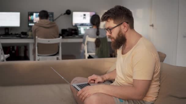 Фрилансер работает с ноутбуком, сидя на диване в коворкинге — стоковое видео