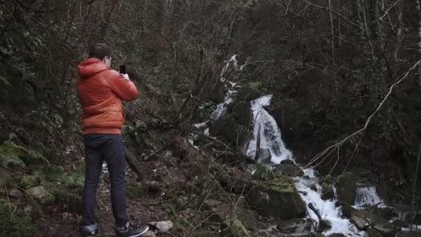 Viajante está fazendo vídeo por seu telefone em uma floresta no outono dia frio — Vídeo de Stock