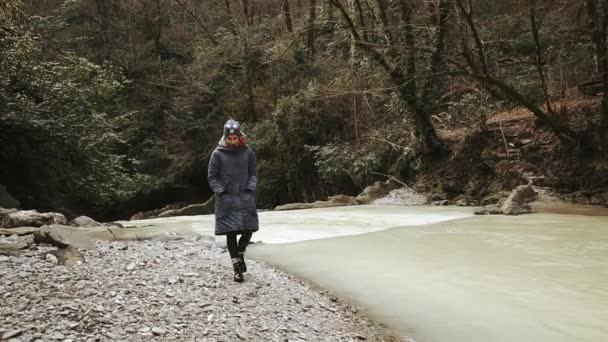 Одинокая грустная девушка бродит возле лесной реки в облачную осеннюю погоду — стоковое видео