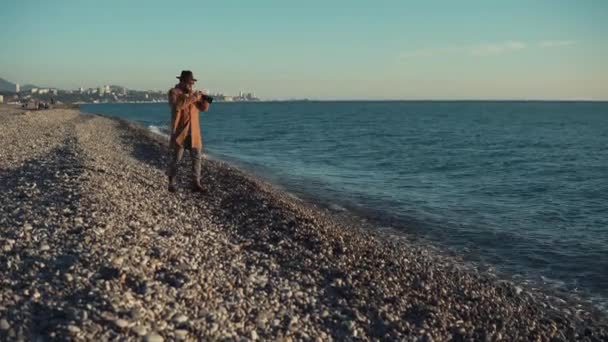 Stadsbo promenerar över grus stranden av havet och att ta foton i soliga dag — Stockvideo