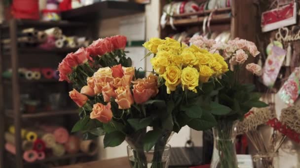 Hermosas rosas rosadas y amarillas están en un jarrón en una florería — Vídeo de stock