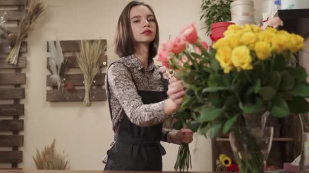 Работница цветочной студии делает декор роз в мастерской — стоковое видео