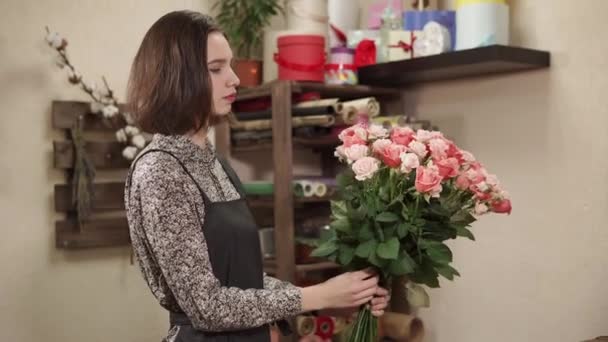 Jong meisje is afwerking te componeren rozen boeket in een floral workshop — Stockvideo