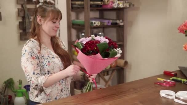 Florist girl is tying bouquet of multicolored flowers by vivid band — Stock Video