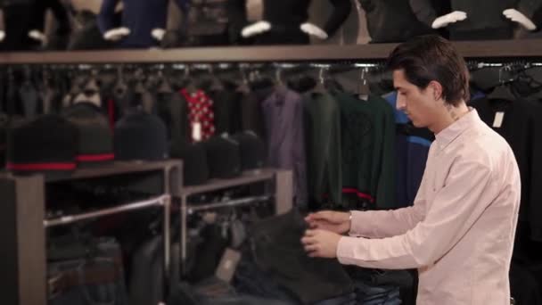 Volwassen man op zoek naar leuke jeans in een winkel — Stockvideo