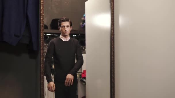 Bello uomo sta provando un maglione nero morbido in uno showroom di negozio di design — Video Stock