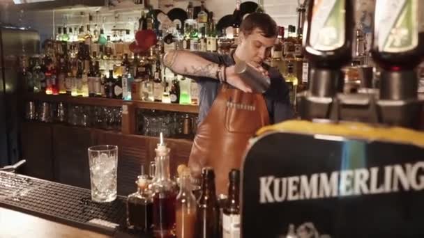 Rosa Khutor, Rusko - únor, 2018:bartender stojí za bar stojanu je míchání koktejlů za dva šálky — Stock video