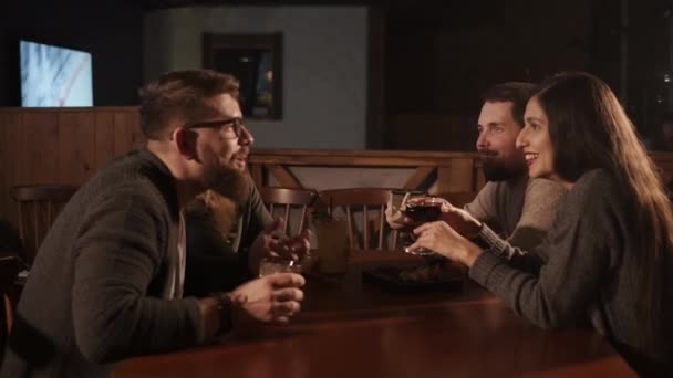 Amigos se comunican en una mesa en un bar, la compañía bebe bebidas alcohólicas — Vídeo de stock