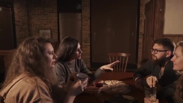 Companhia de mulheres e homens sentam-se a uma mesa com comida e coquetéis em seus óculos — Vídeo de Stock