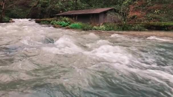Крупным планом снимок реки, которая впадает в водопад, рядом с домом Шато — стоковое видео