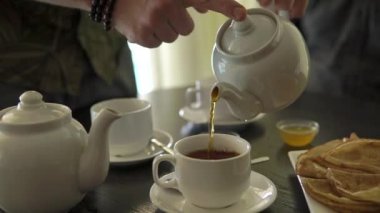 yakın çekim yukarı eller, adamın çay çaydanlık bardak içine dökülen