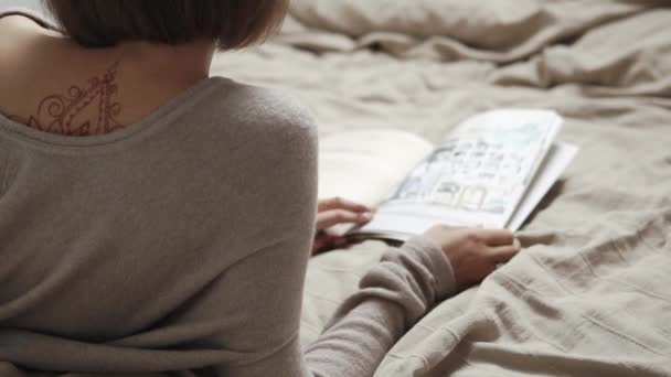 Mujer encantadora con una revista en la cama — Vídeo de stock