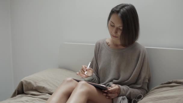 Vrouw houdt van een tablet in haar handen en komt met een mandala, die ze tekent — Stockvideo