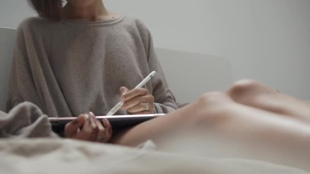 Woman is browsing sites in internet using stylus and flatbed computer in bedroom — Stock Video