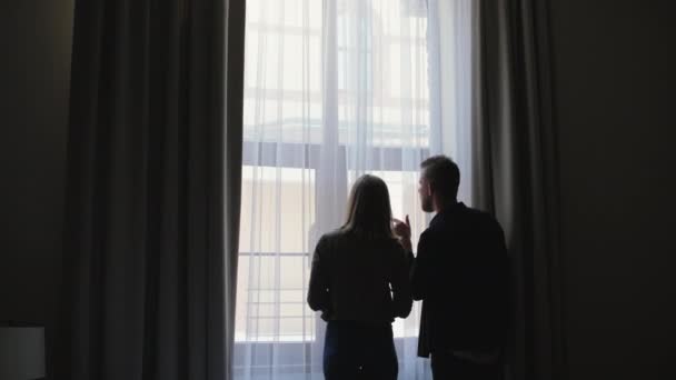 Muž a žena se dívají do okna — Stock video