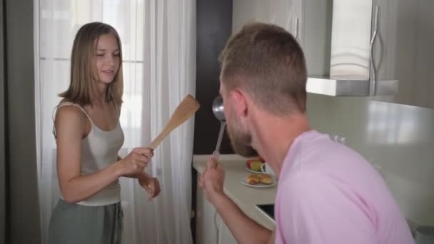 Hombre y mujer están luchando por los aparatos de cocina en broma en la cocina — Vídeos de Stock