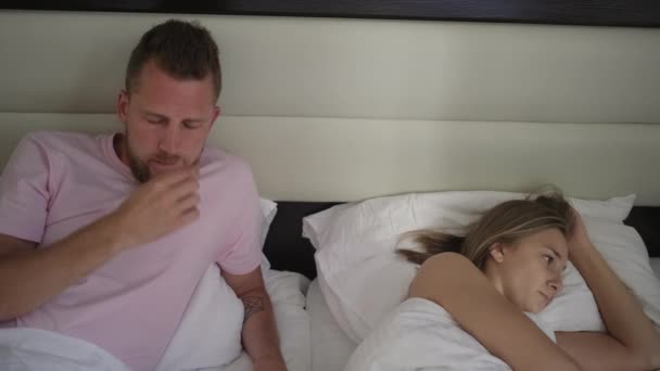 Man zit in bed in de buurt van zijn beledigde vrouw na vloeken — Stockvideo