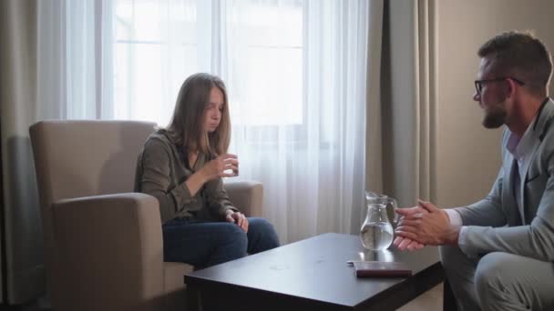 Depresyondaki kadın psikoterapist adamın odasında su içiyor. — Stok video