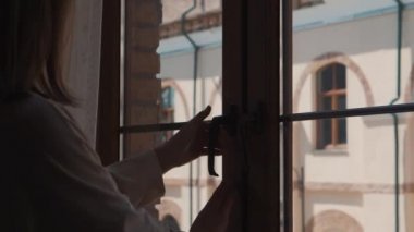 Kadın pencereyi açıyor ve sokağa bakıyor.