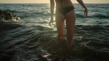 Kadın yazın denize giriyor ve suda yüzüyor.