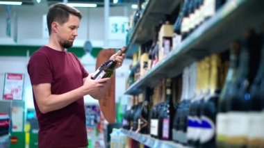 Adam markette şampanya şişesinin etiketini okuyor.