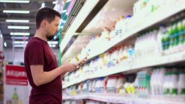 Erkek müşteri süt reyonunda yoğurt seçiyor.