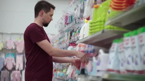 Мужчина выбирает детскую горшочку в супермаркете — стоковое видео