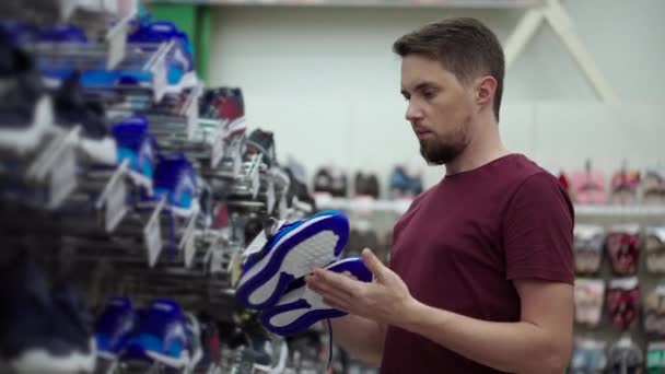 Hombre está eligiendo zapatos deportivos en la tienda de calzado — Vídeos de Stock