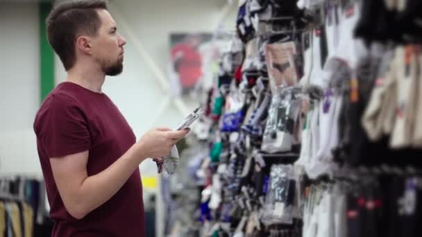 Hombre está comprando calcetines en el supermercado en la sala de venta — Vídeos de Stock