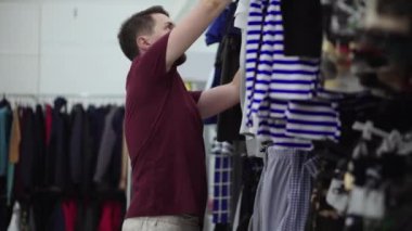 Alıcı, giyim mağazasının ticaret alanında tişört seçiyor.