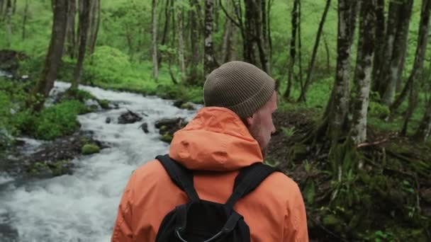 Samotny turysta rozgląda się po lesie z rzeką — Wideo stockowe