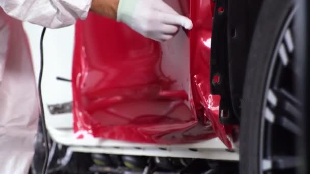 Mann streift schützende Vinylhülle an Kante der Autotür — Stockvideo